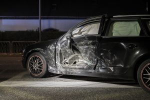 A car after an accident severely damaged the driver’s side with the side airbags deployed.
