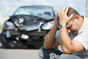 stressed man by totaled black car