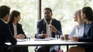 a male arbitrator discussing a car accident with three women and one man at a table.