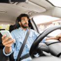 A man driving while distracted. A lawyer can help you with examining distracted driving statistics.